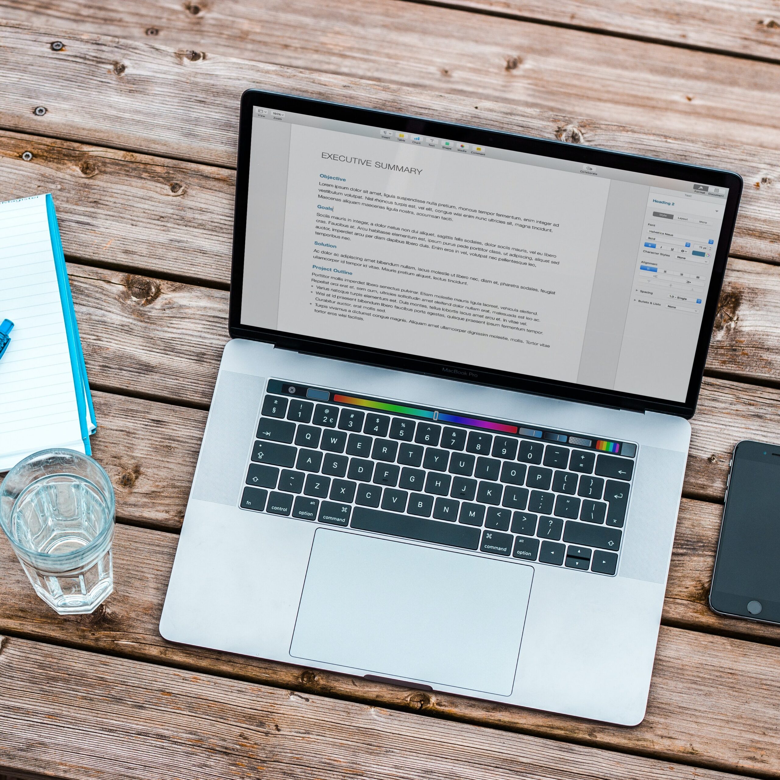 A grey laptop displaying a resume on a wooden desk. 