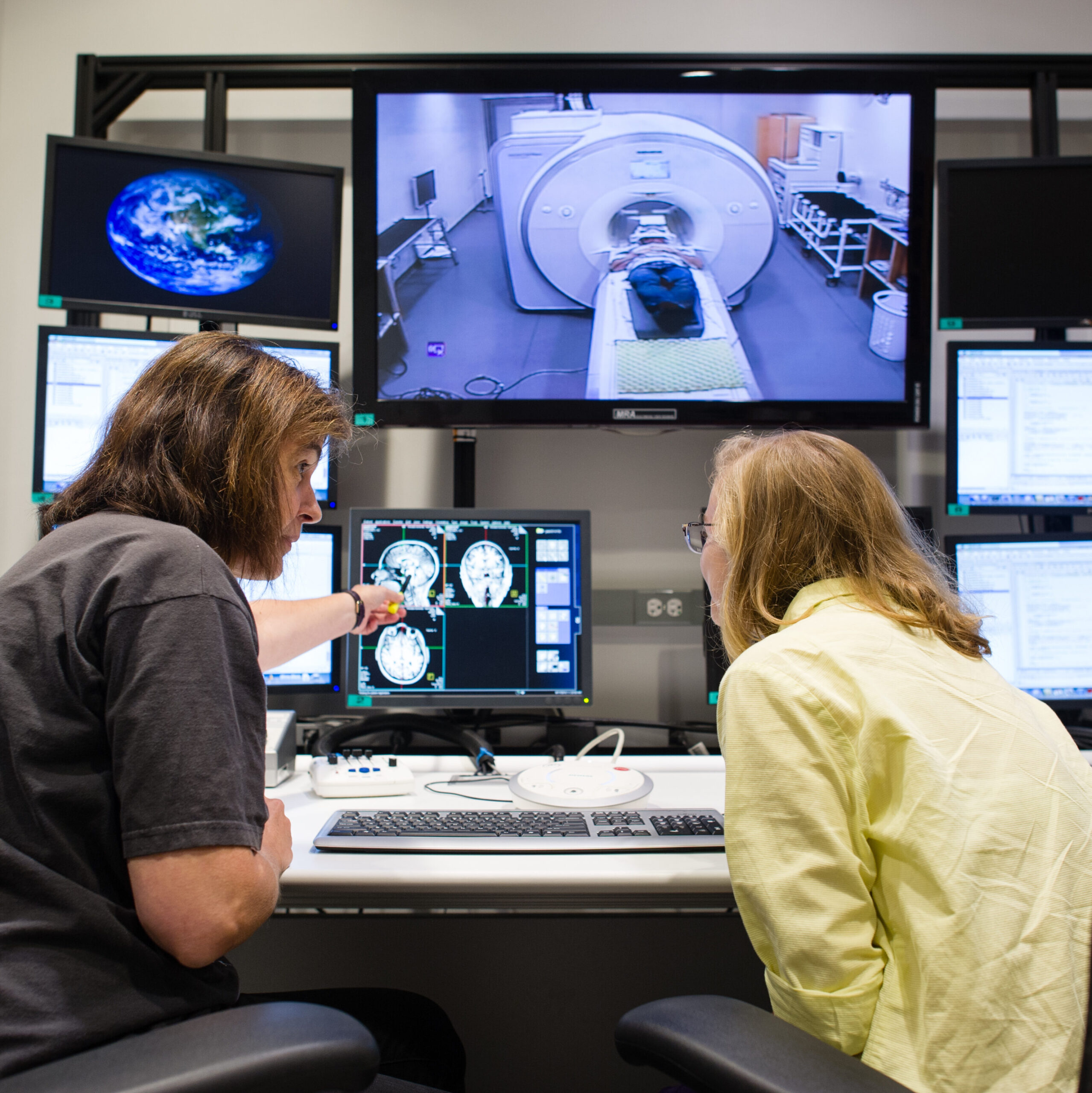 Two researchers sitting at a lab desk in the Princeton Neuroscience Institute, looking at MRI brain scans on a computer.