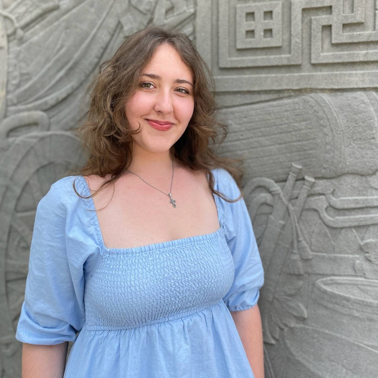 Image of interview subject, Katya Grygorenko in front a stone wall with artictic carvings.