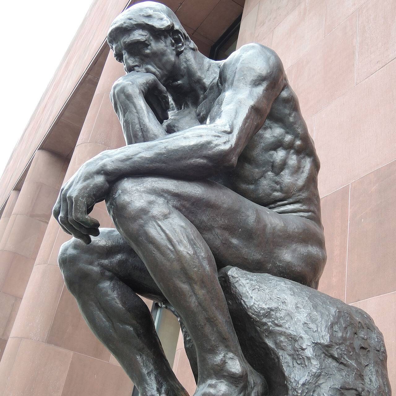 A statue of a man sitting on a rock, thinking
